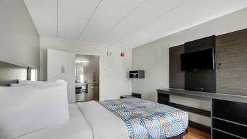 Una habitación de hotel moderna con una cama grande, un televisor de pantalla plana en la pared y una zona de kitchenette.