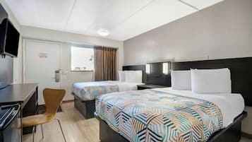A hotel room with two beds, a desk, a chair, and a television.