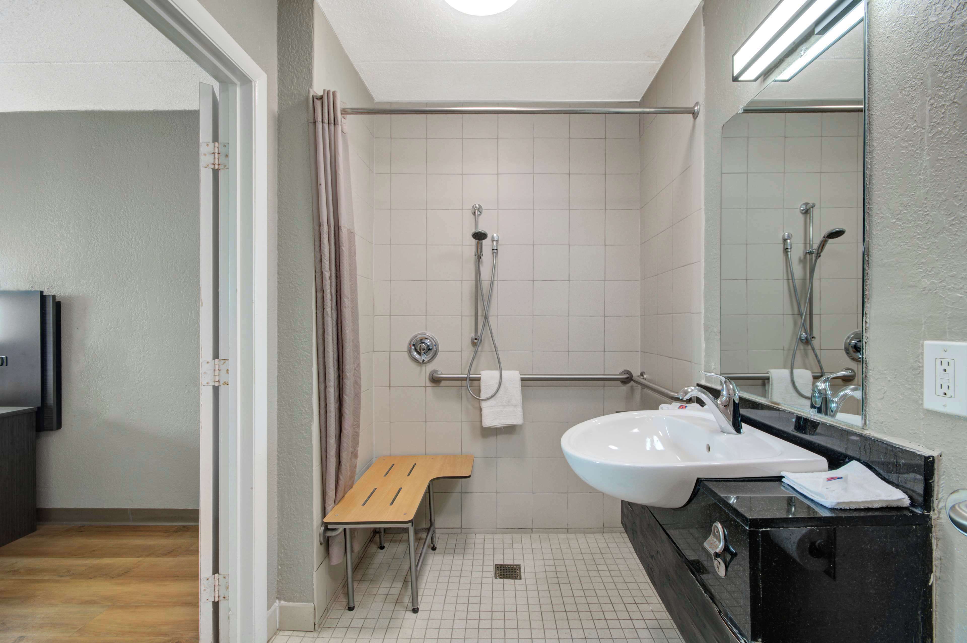 Ein modernes Badezimmer mit Dusche, Waschbecken und einem kleinen hölzernen Hocker.