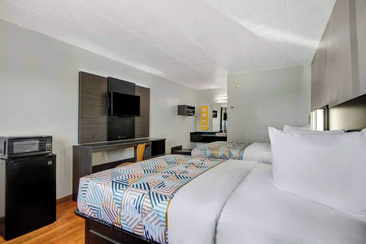 A hotel room with a bed, a desk, a TV, and a microwave.