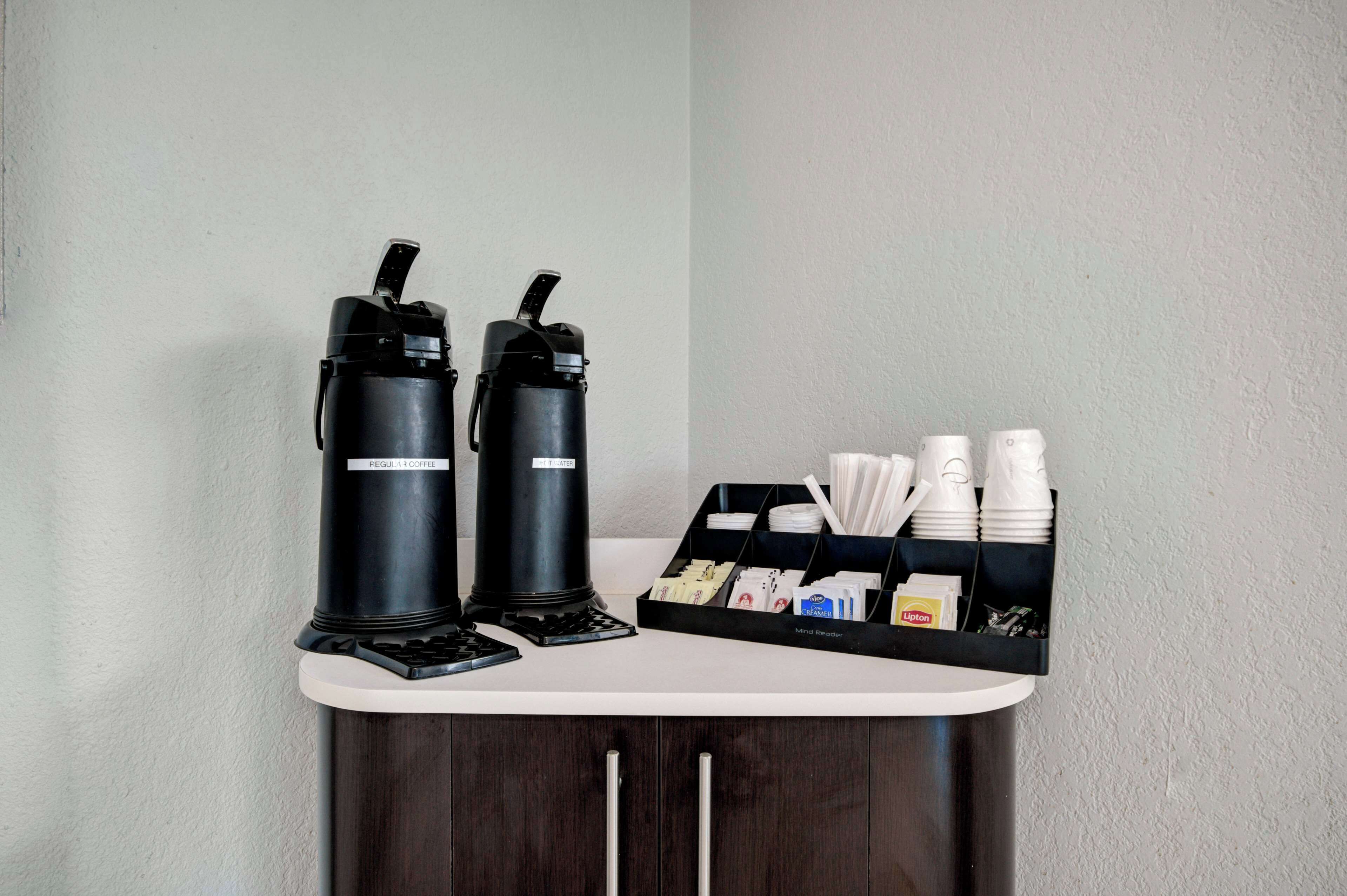 A coffee station with two coffee makers and a tray of disposable cups and napkins.