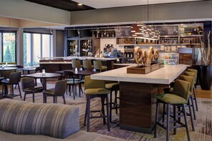 Un espace bar moderne doté d’un îlot central, de tabourets de bar et d’une variété de bouteilles et de verres.