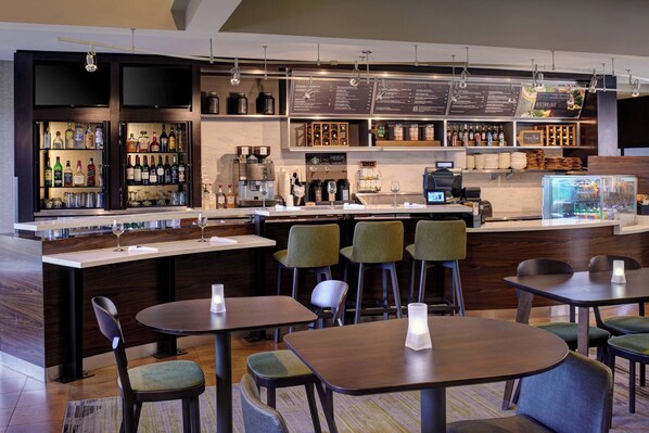 Uma área de bar moderna com balcão, banquetas e um quadro de cardápio.