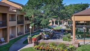A courtyard with outdoor seating, a flower garden, and a building with balconies. - Courtyard by Marriott Detroit Dearborn (Dearborn)