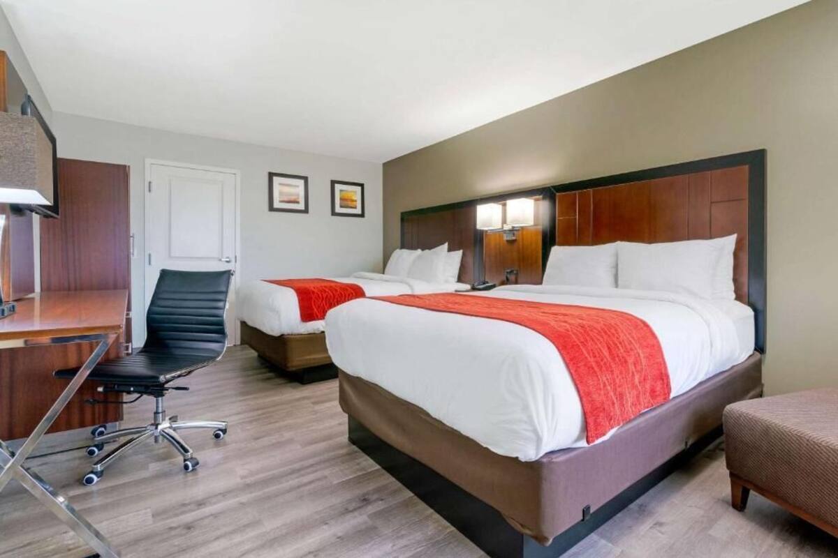 A hotel room with two beds, a desk, and a chair.