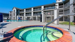 A hotel with a swimming pool, outdoor seating, and a multi-story building with balconies.