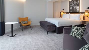 Una habitación de hotel con una cama, un sofá, una mesita y una silla.