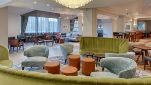 A spacious lobby with a green sofa, armchairs, and a chandelier. - DoubleTree by Hilton London Elstree (Borehamwood)