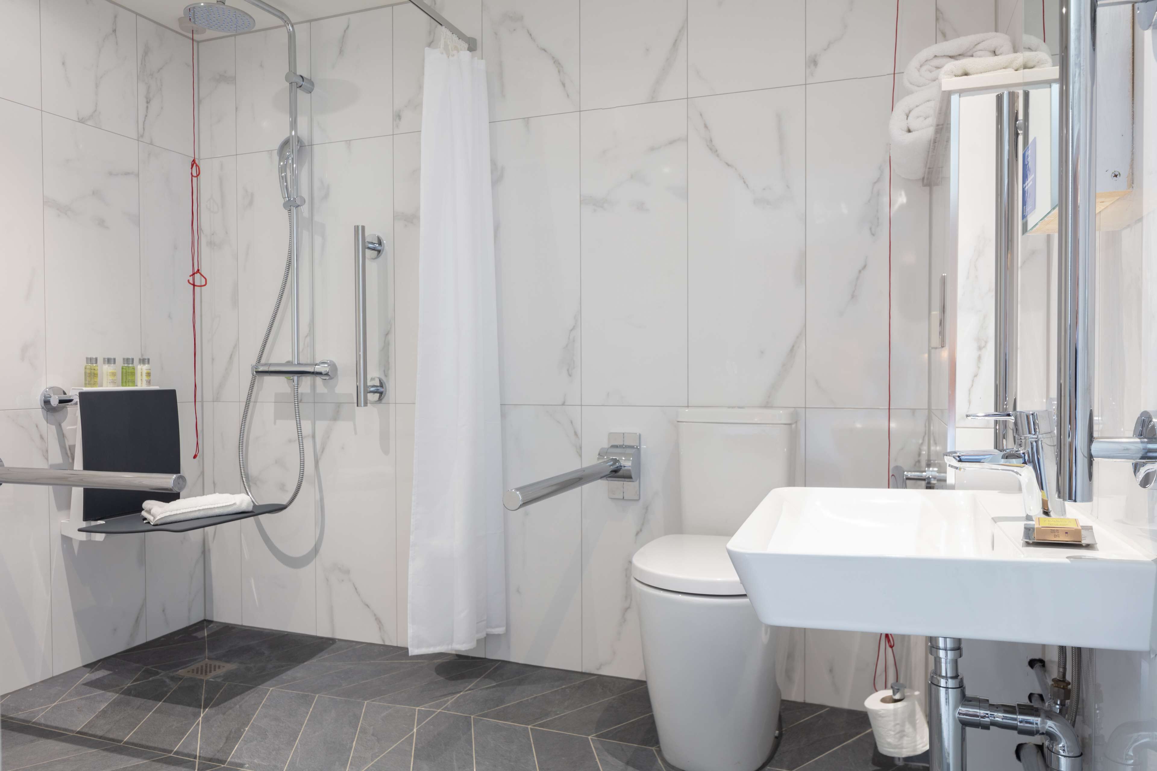 A modern bathroom with a shower, toilet, and sink.