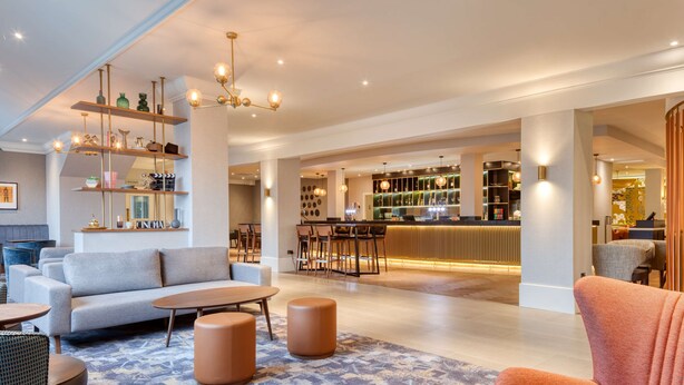 A spacious lobby with a bar area, seating arrangements, and a patterned carpet. - DoubleTree by Hilton London Elstree (Borehamwood)