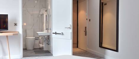 Une salle de bain moderne équipée de toilettes, d’un lavabo et d’un porte-serviettes.
