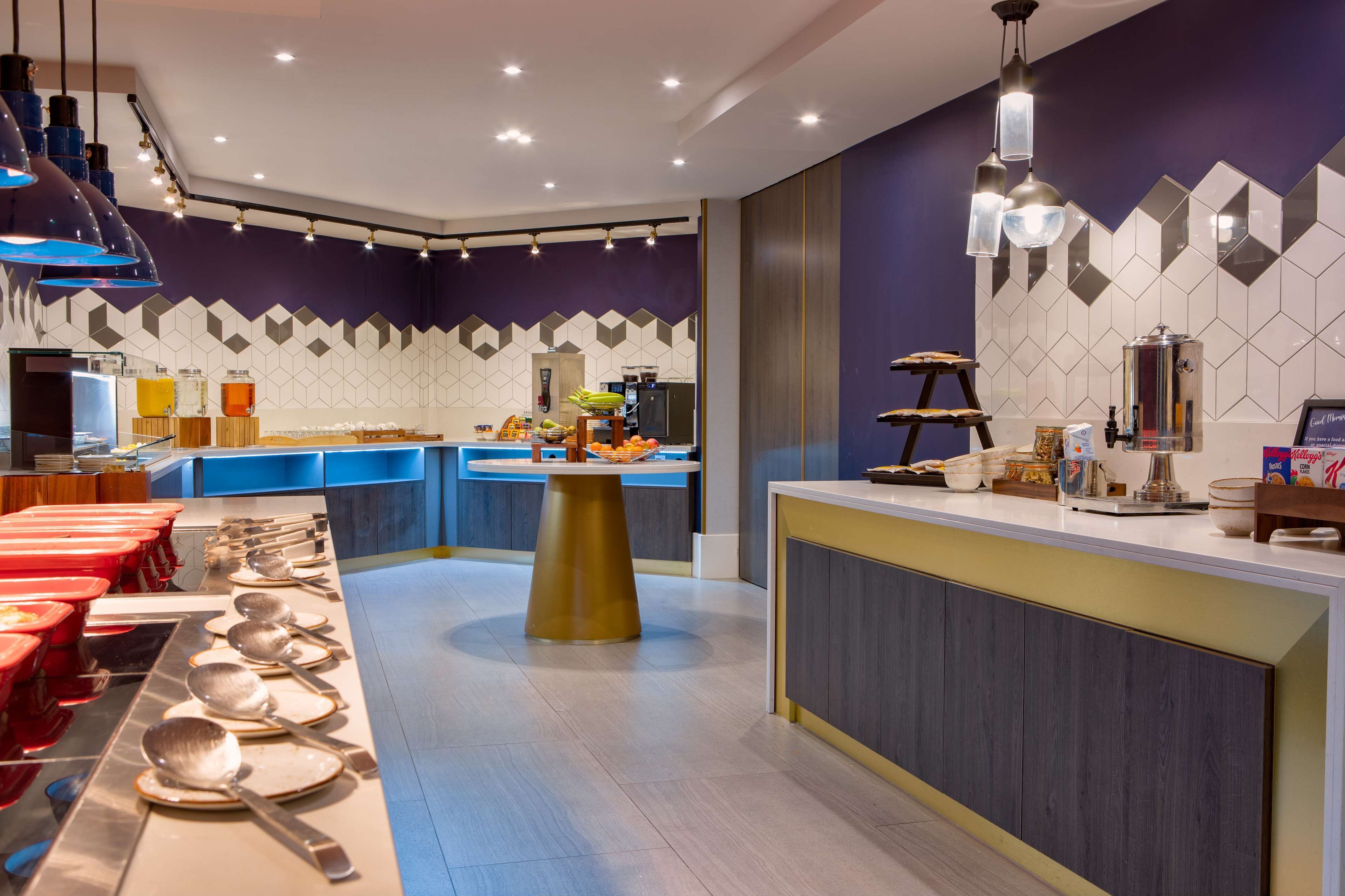 A modern buffet setup with multiple serving stations, a central island, and a variety of food items.