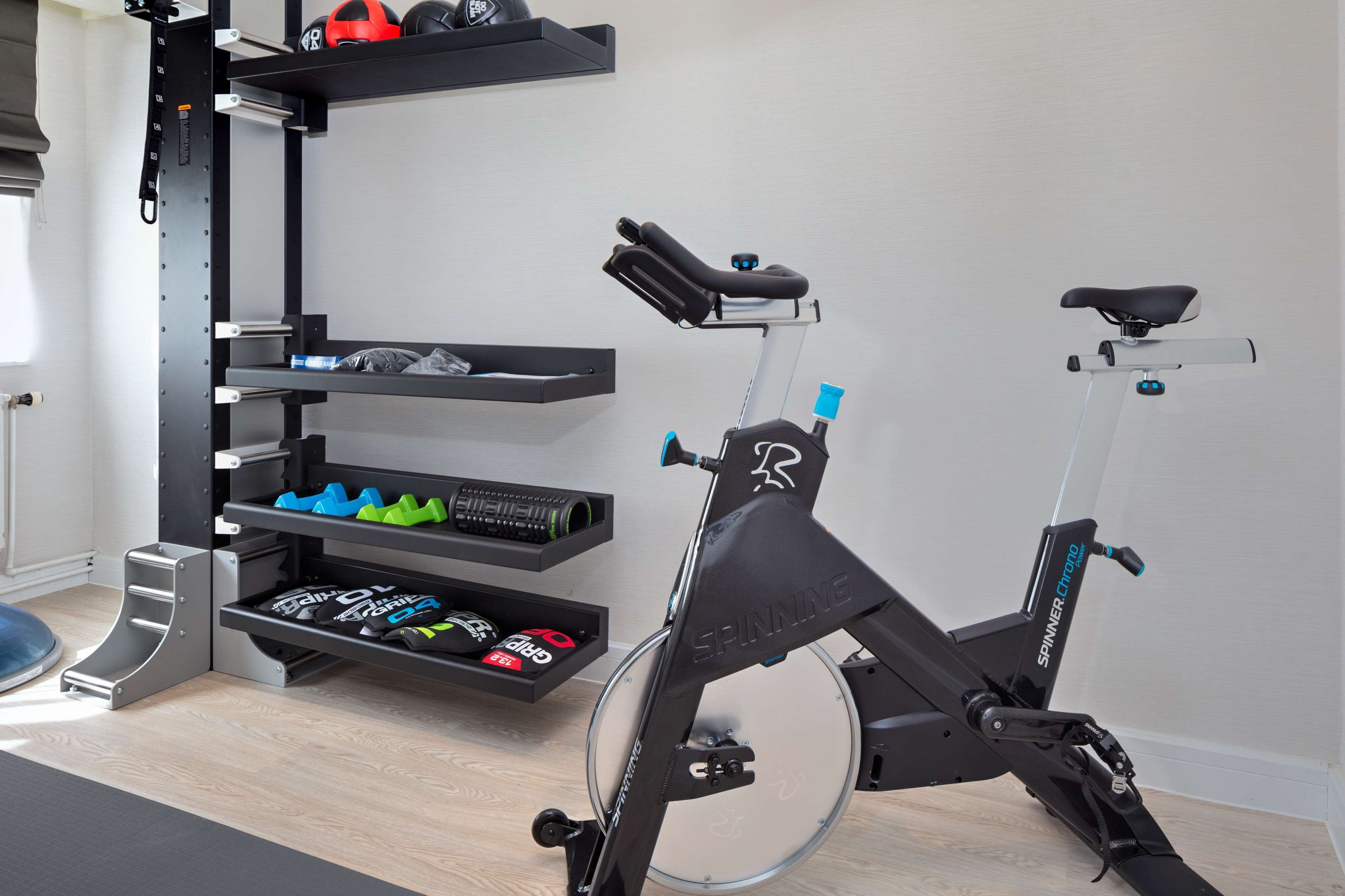 Une salle de sport à domicile équipée d’un vélo d’appartement, de supports pour les poids et d’un matériel d’exercice rangé de manière ordonnée.