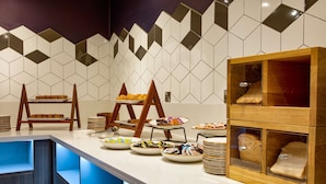 A buffet setup with various food items and a bread display. - DoubleTree by Hilton London Elstree (Borehamwood)