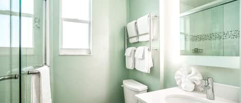 Un baño con inodoro, lavamanos y cabina de ducha de vidrio.