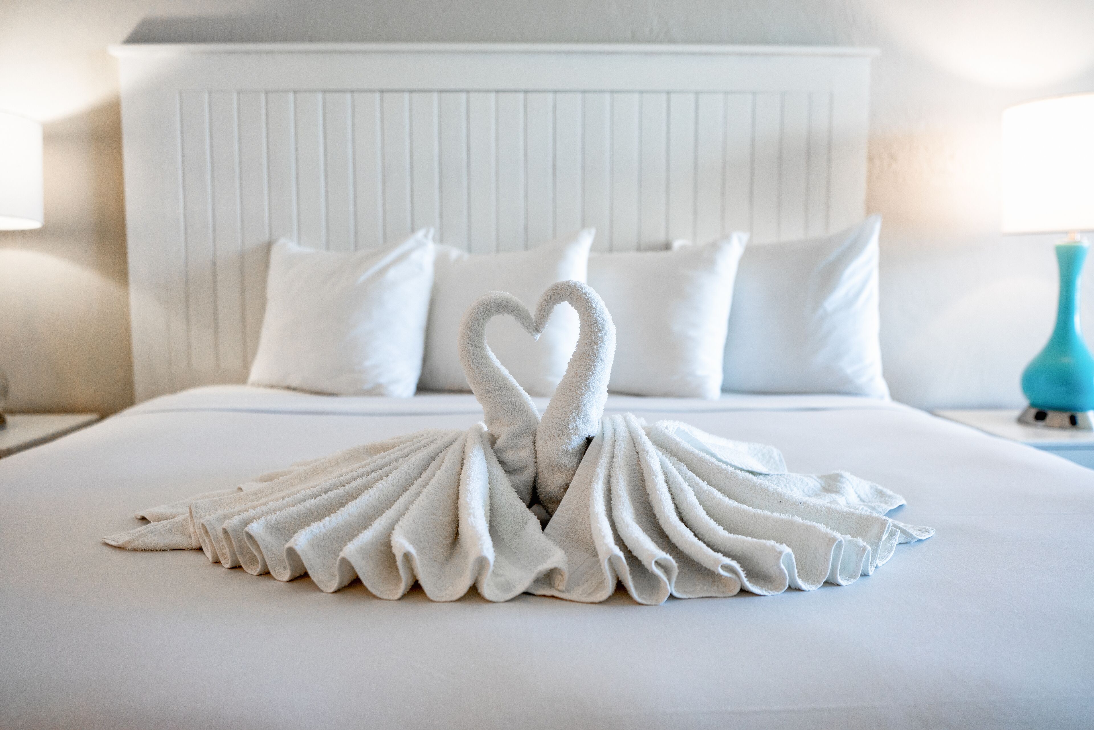 Una cama bien hecha con una decoración de toallas con forma de corazón en el centro.