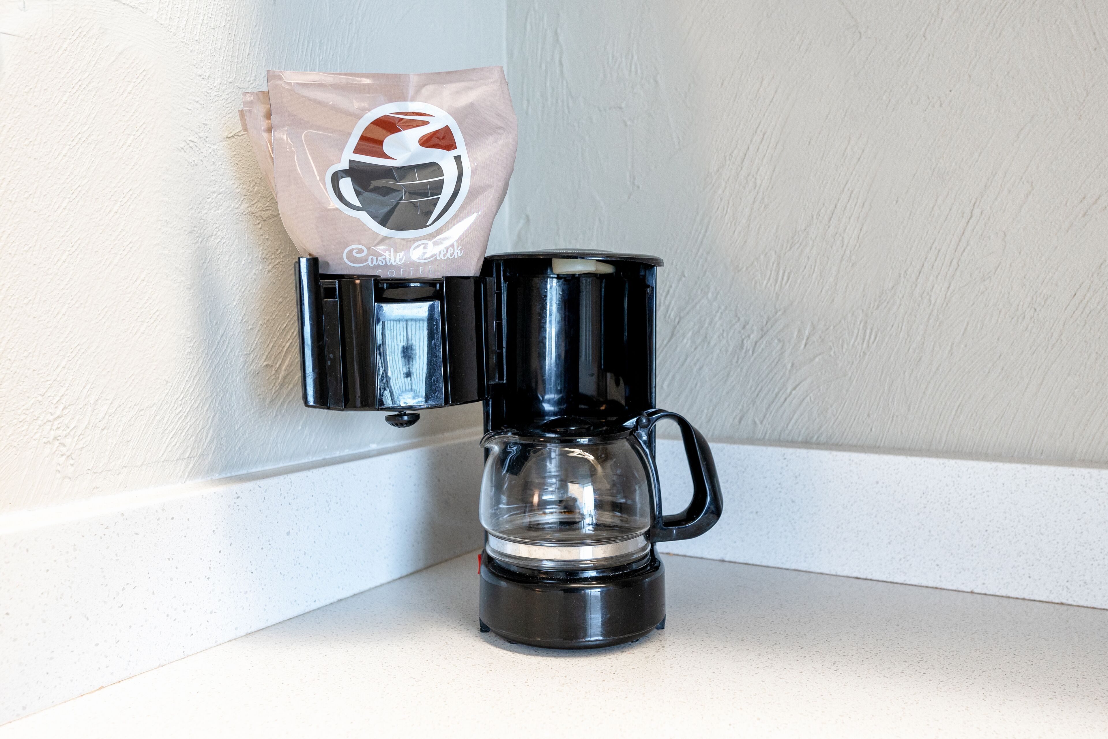 A coffee maker with a bag of coffee pods on a white countertop.