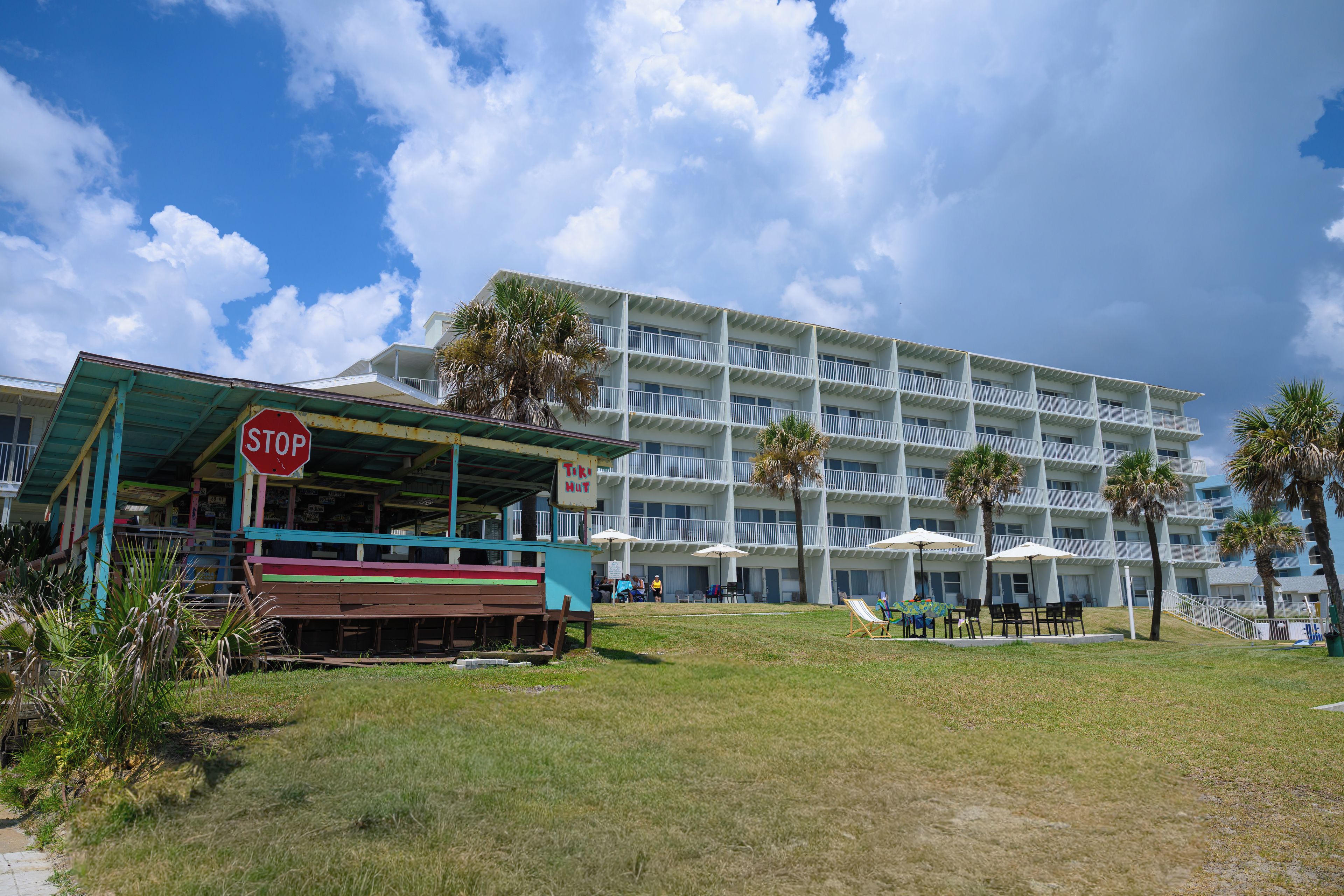 A beachfront hotel with a stop sign, outdoor seating, and palm trees.