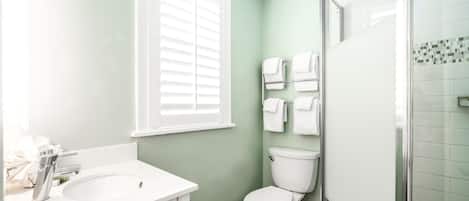 A bathroom with a white sink, toilet, and shower.