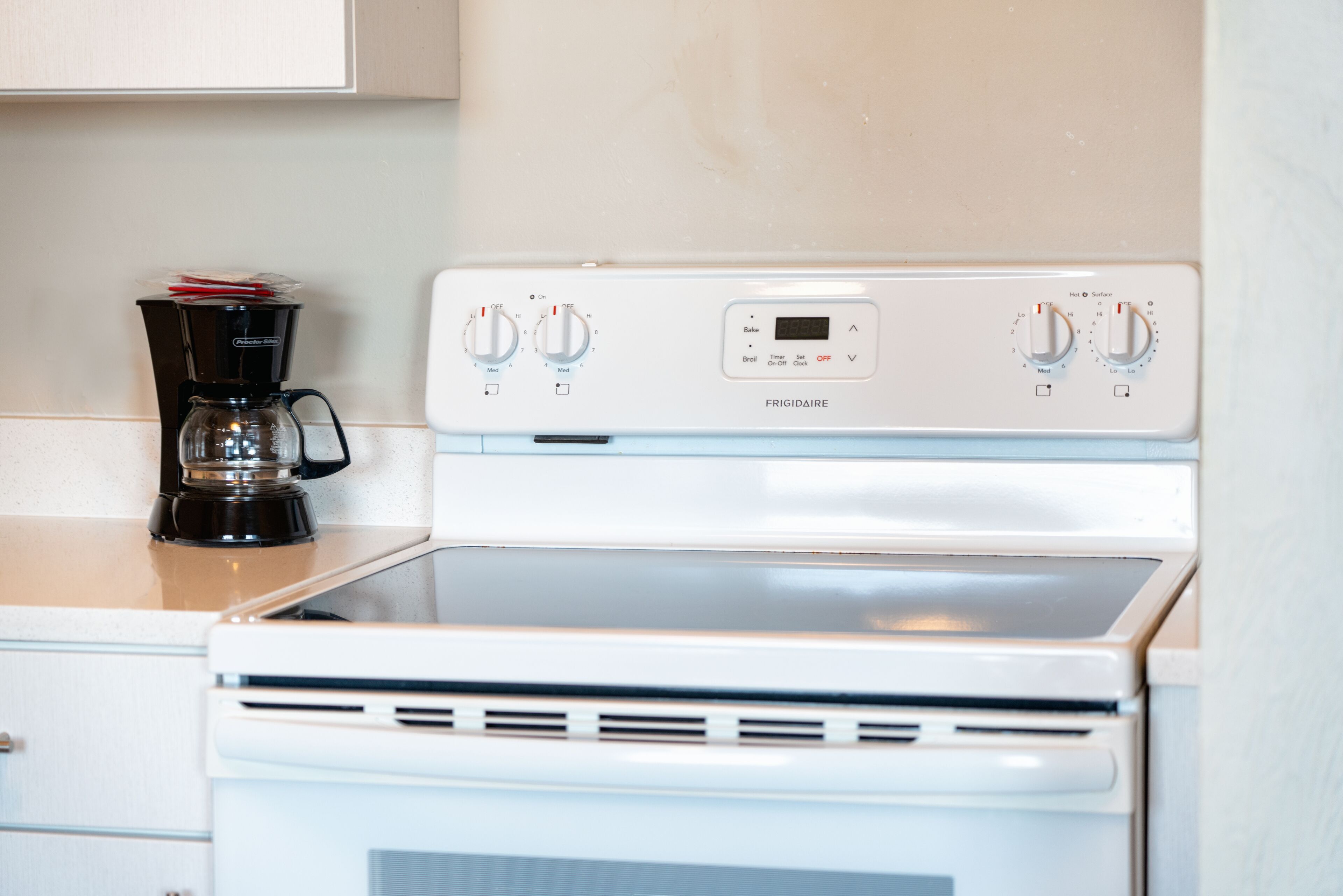 A kitchen with a white stove and a coffee maker on the counter.