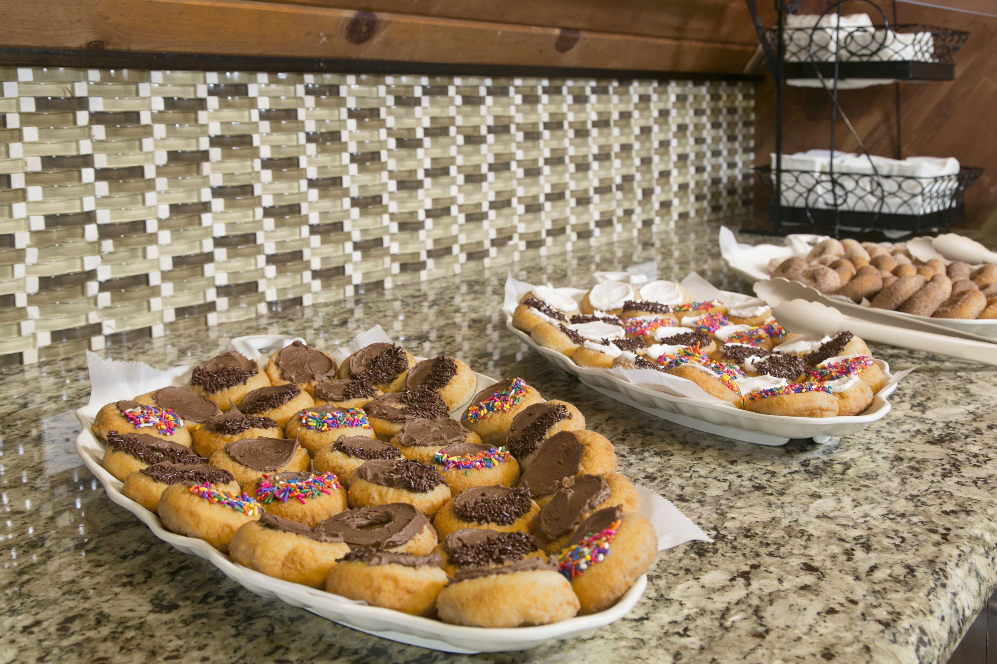 A kitchen counter with trays of decorated doughnuts and a decorative wall.
