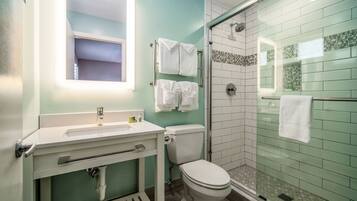 A bathroom with a toilet, sink, and glass shower enclosure.