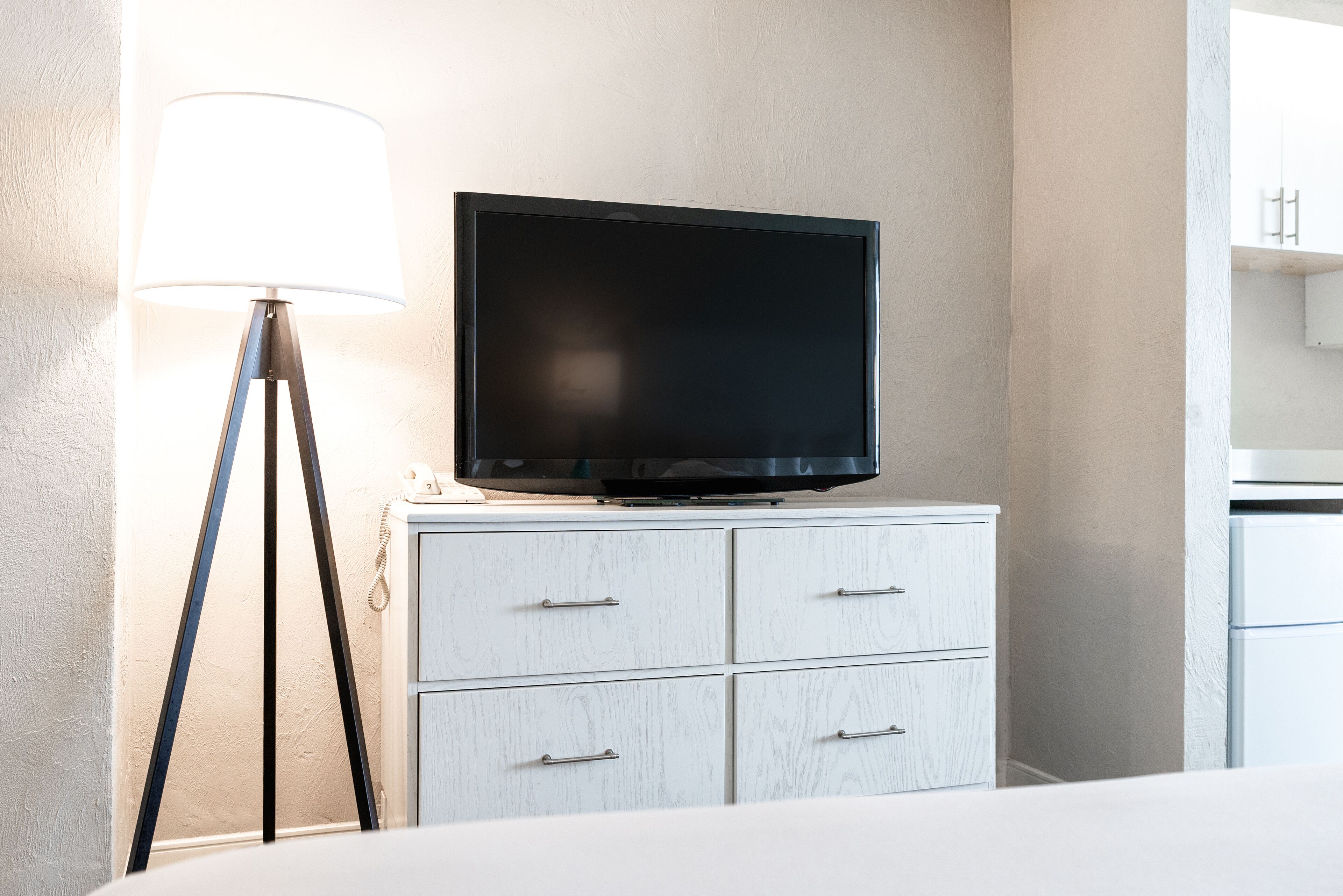 Un televisor sobre un tocador blanco en una habitación de hotel.