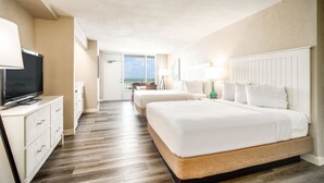 Une chambre d’hôtel avec deux lits, une télévision, un bureau et un balcon avec vue.