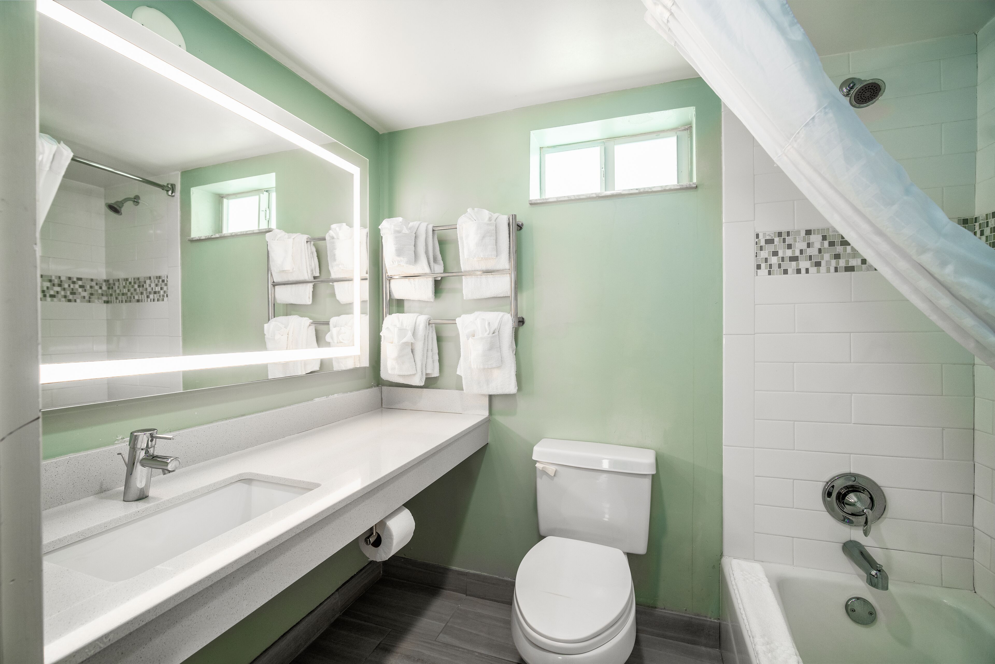 A bathroom with a white sink, toilet, and bathtub. There are towels hanging on a rack and a shower curtain.