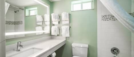 A bathroom with a white sink, toilet, and bathtub. There are towels hanging on a rack and a shower curtain.