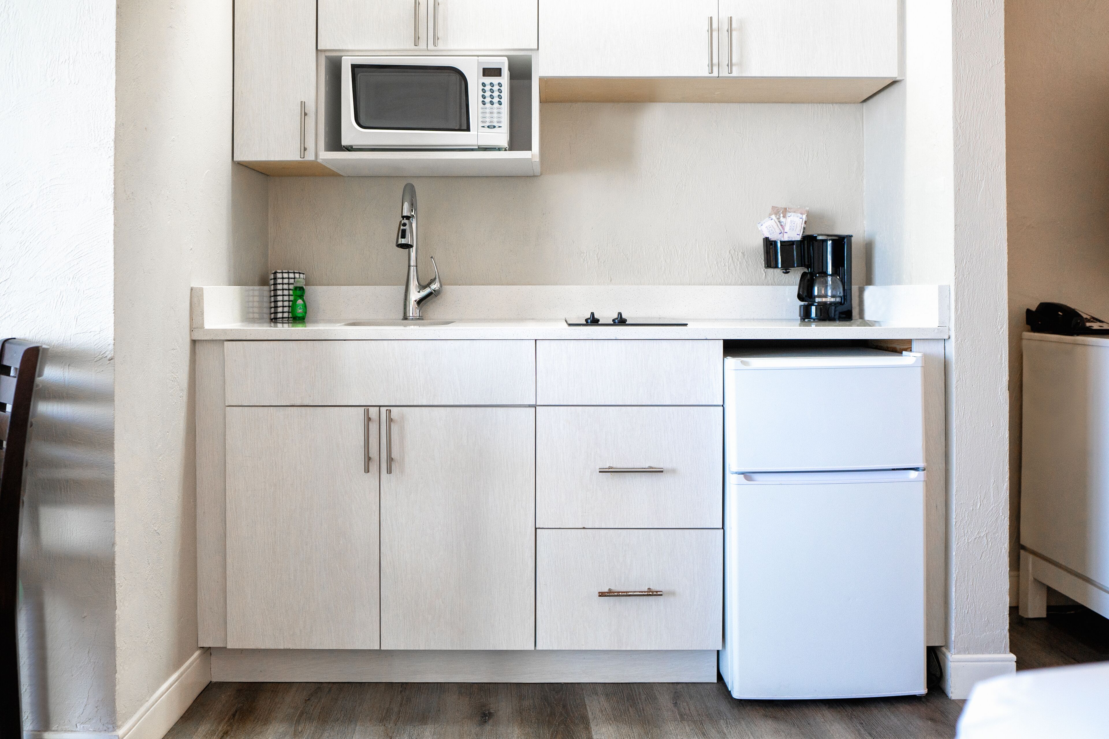 Una cocina compacta equipada con microondas, cafetera y refrigerador.