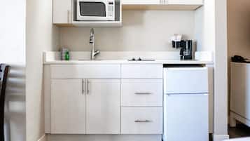 Una cocina compacta equipada con microondas, cafetera y refrigerador.