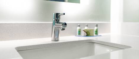 A modern bathroom with a chrome faucet, a white sink, and a mirror above it.