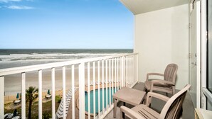 Un balcon avec une piscine, des chaises et une vue sur la plage et l’océan.