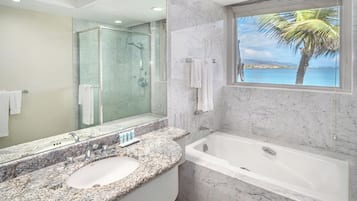 A modern bathroom with a marble sink, a bathtub, and a glass-enclosed shower.