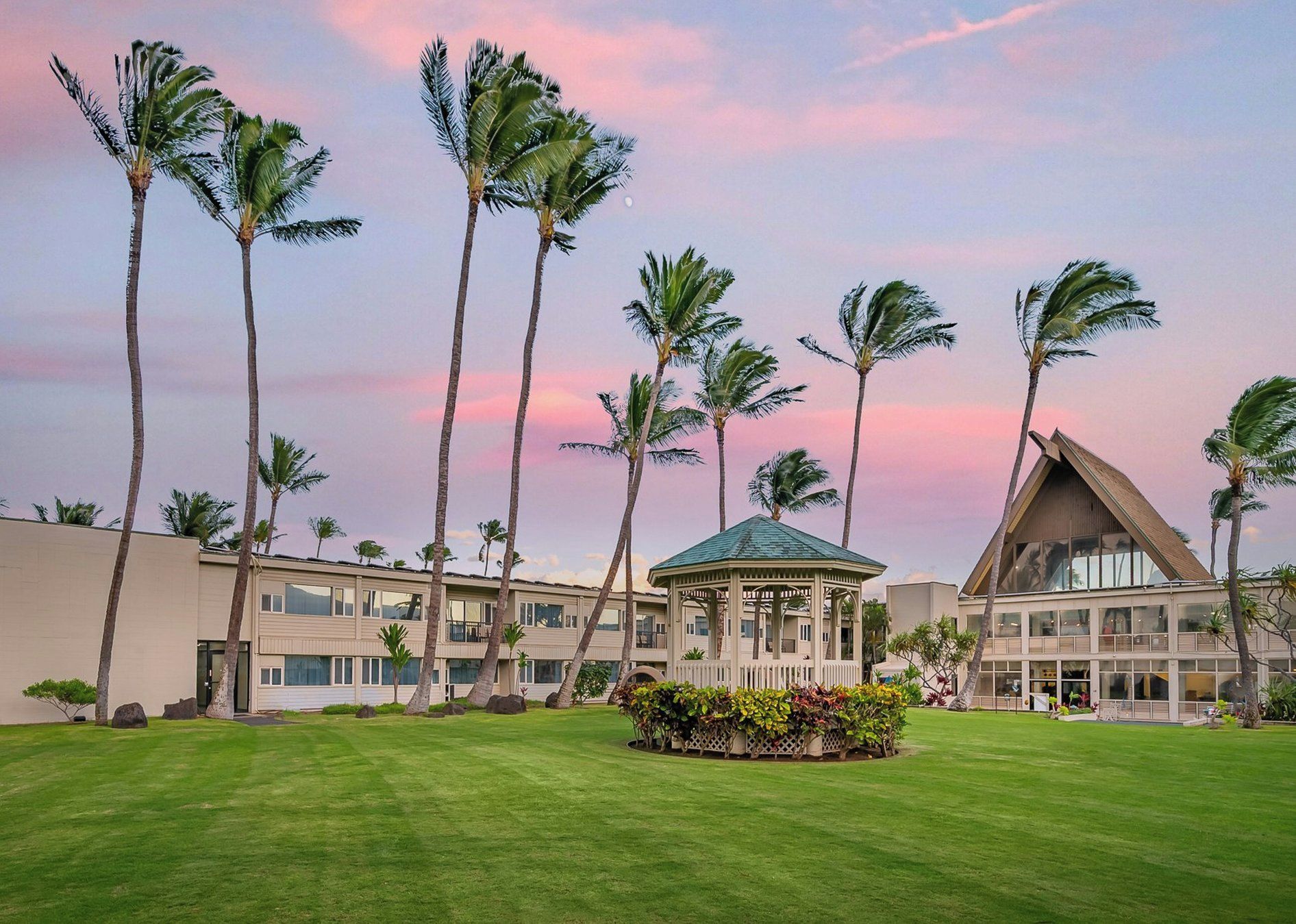 A hotel with multiple-story buildings, a central gazebo, and palm trees.