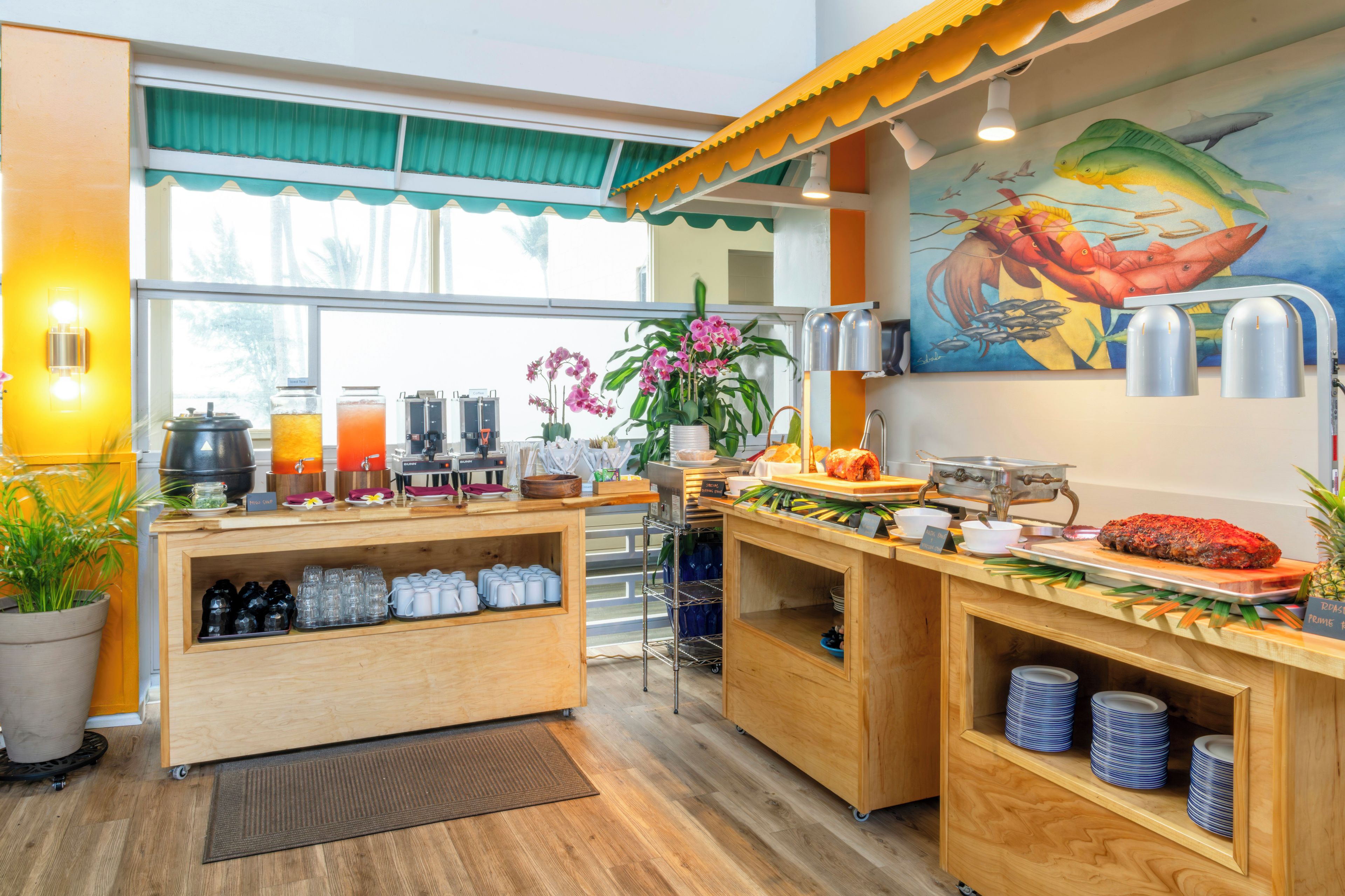 A breakfast buffet area with a variety of food options, a coffee station, and a mural of sea creatures on the wall.