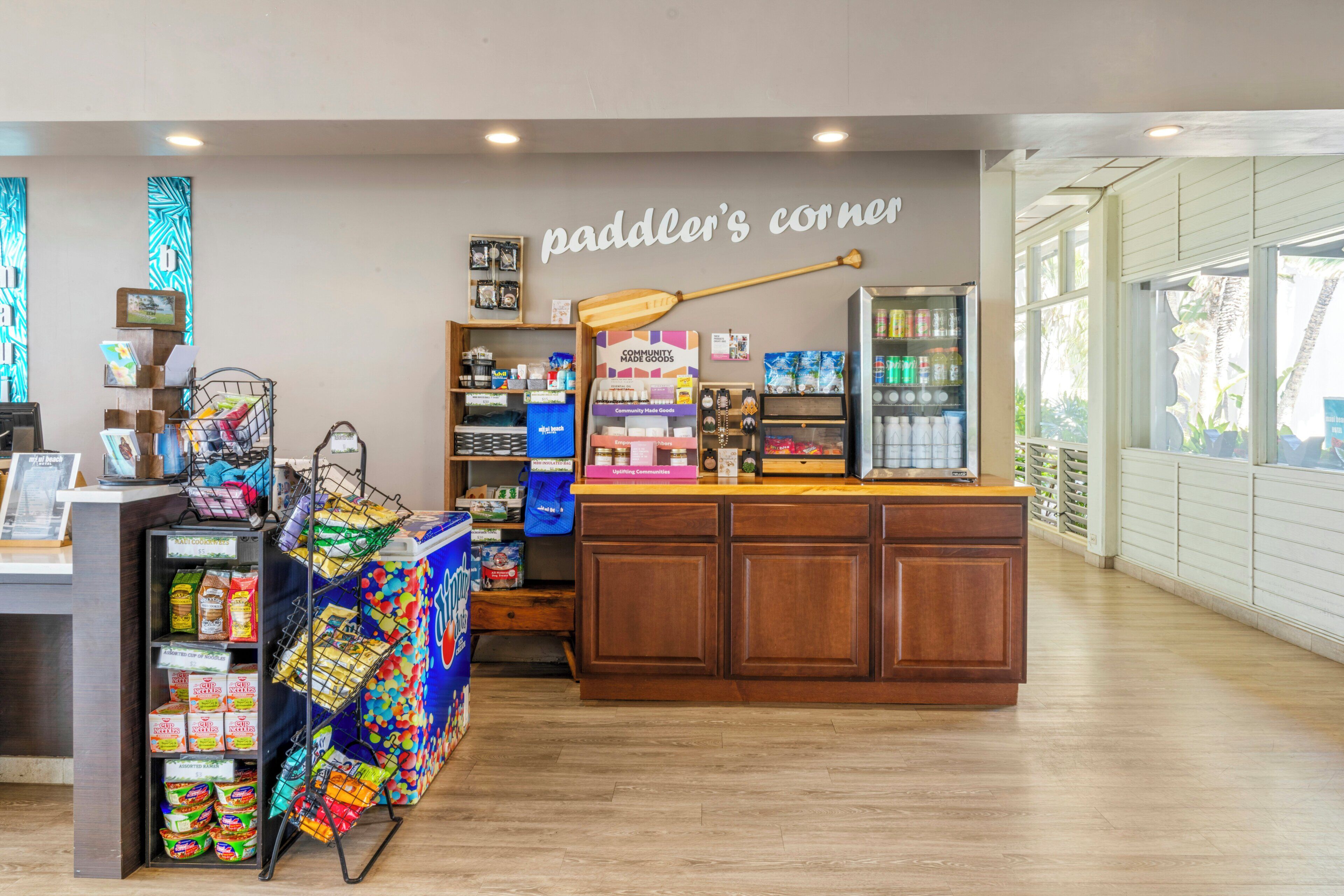 Tienda con mostrador de madera, diversos productos envasados y un letrero en la pared que dice 'paddler's corner'.