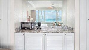 A kitchen with a view of the ocean, a ceiling fan, and a coffee maker. - Maui Beach Hotel (Kahului)