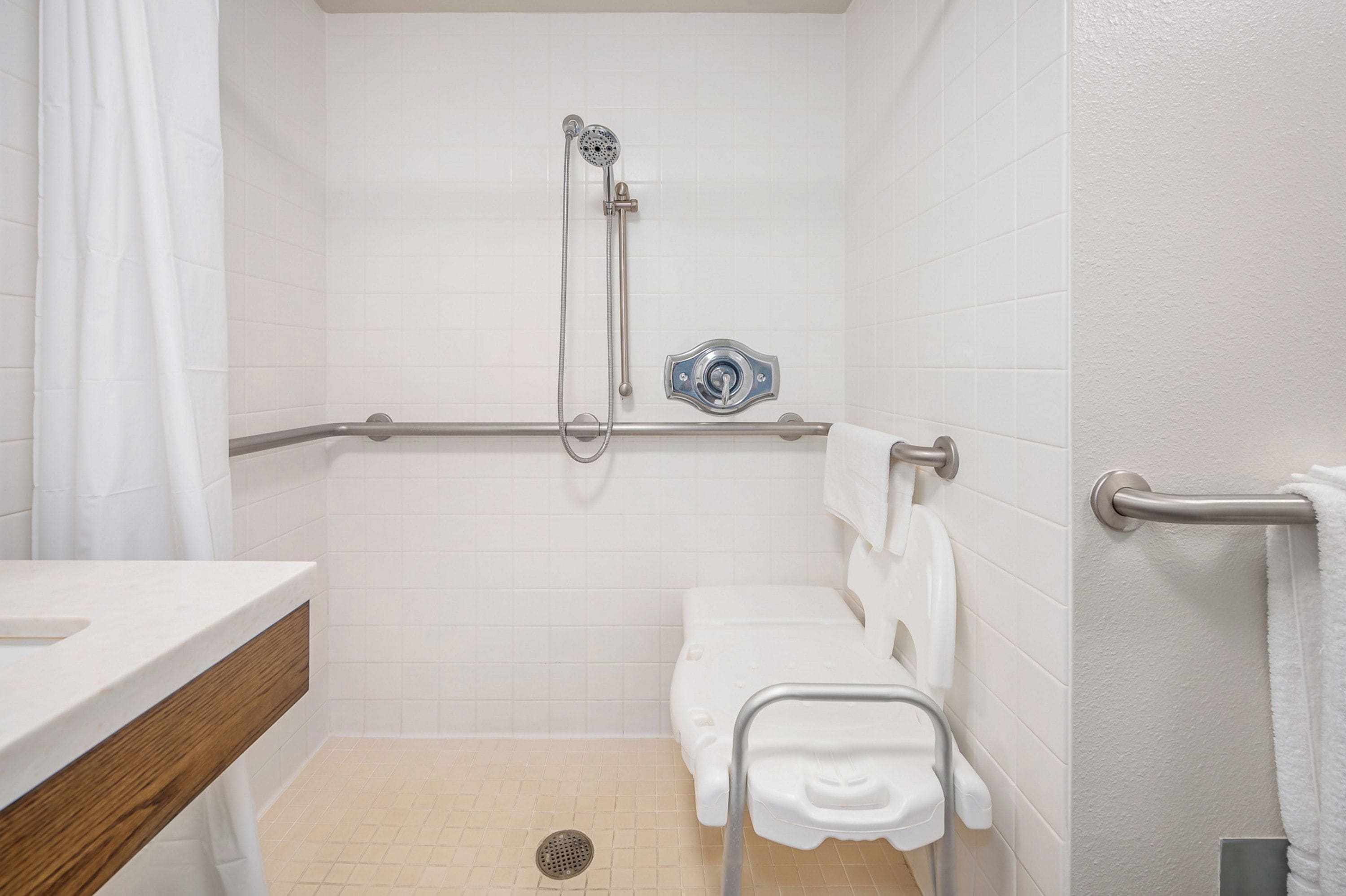 A bathroom with a shower, toilet, and grab bar.