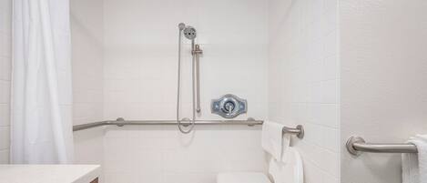 A bathroom with a shower, toilet, and grab bar.