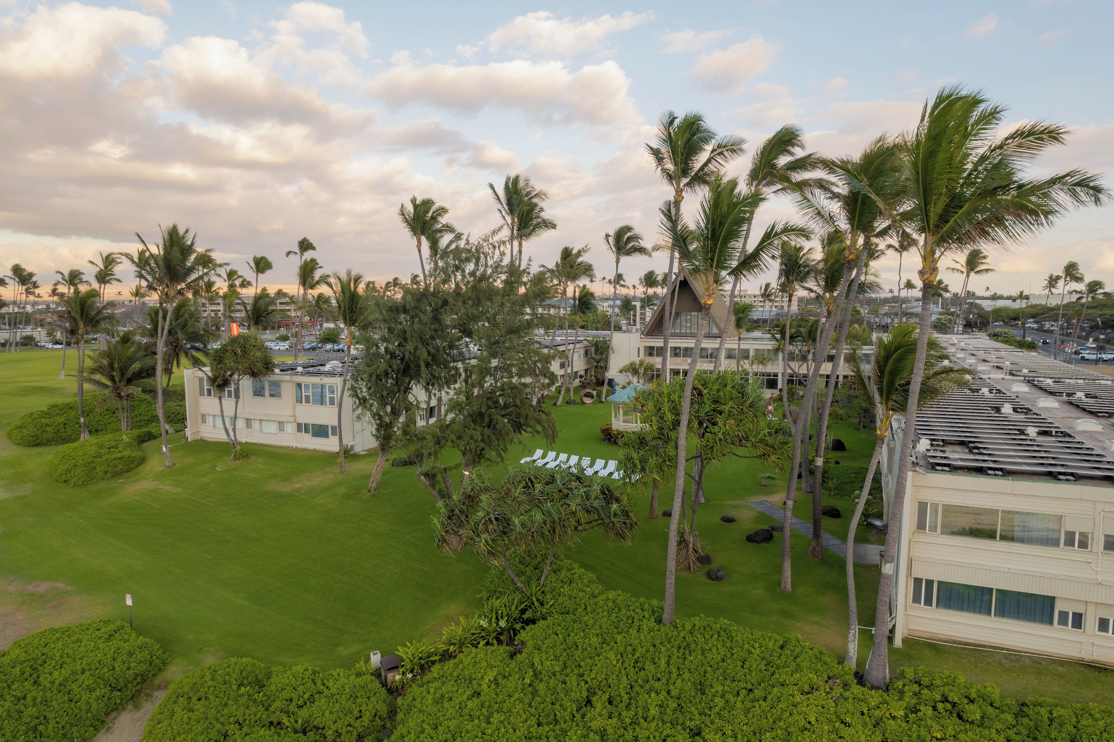 A resort with multiple buildings, palm trees, and a well-maintained lawn.