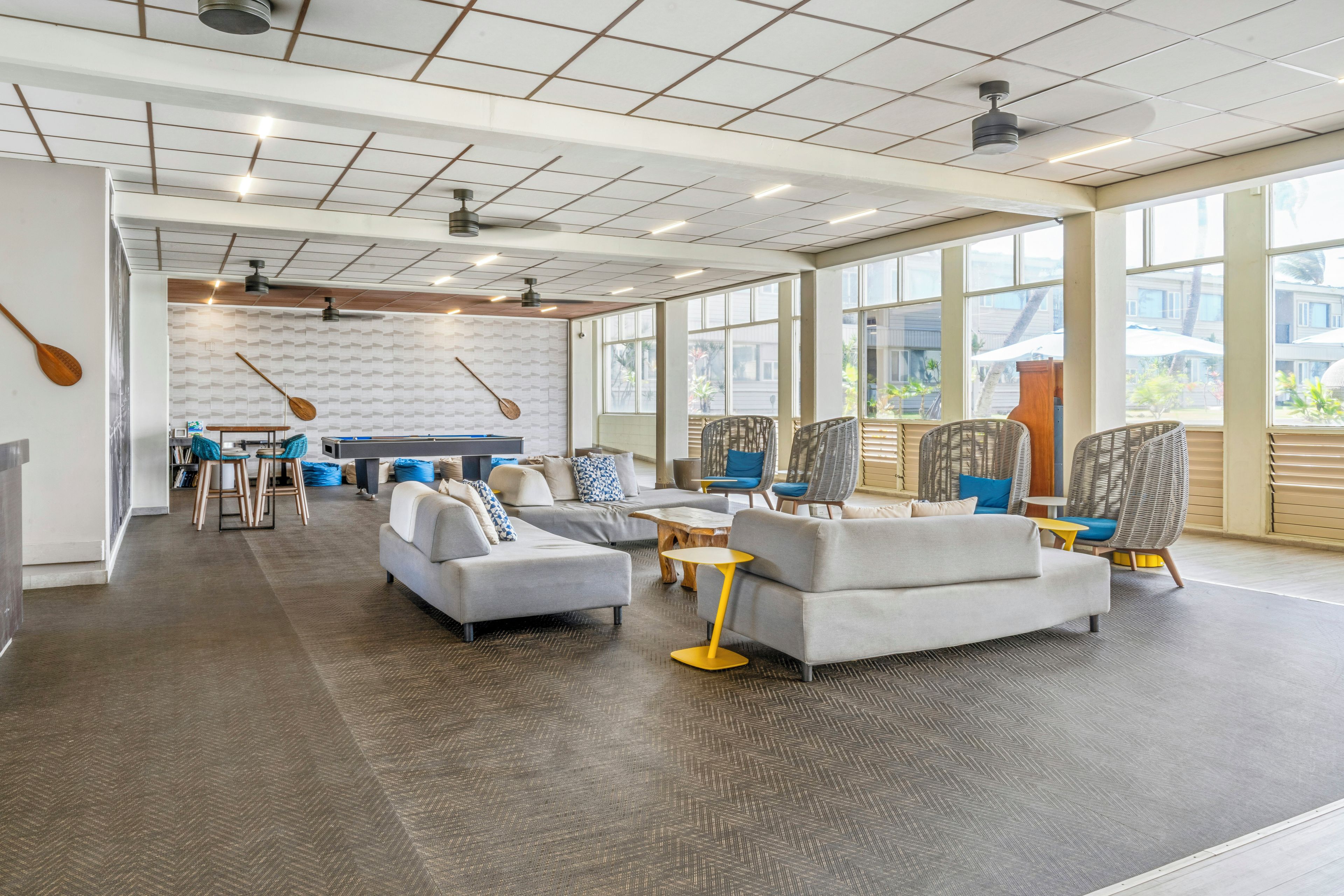 A spacious lounge area with sofas, chairs, and a pool table.