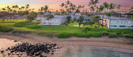 A resort with beachfront properties, palm trees, and a clear sky.