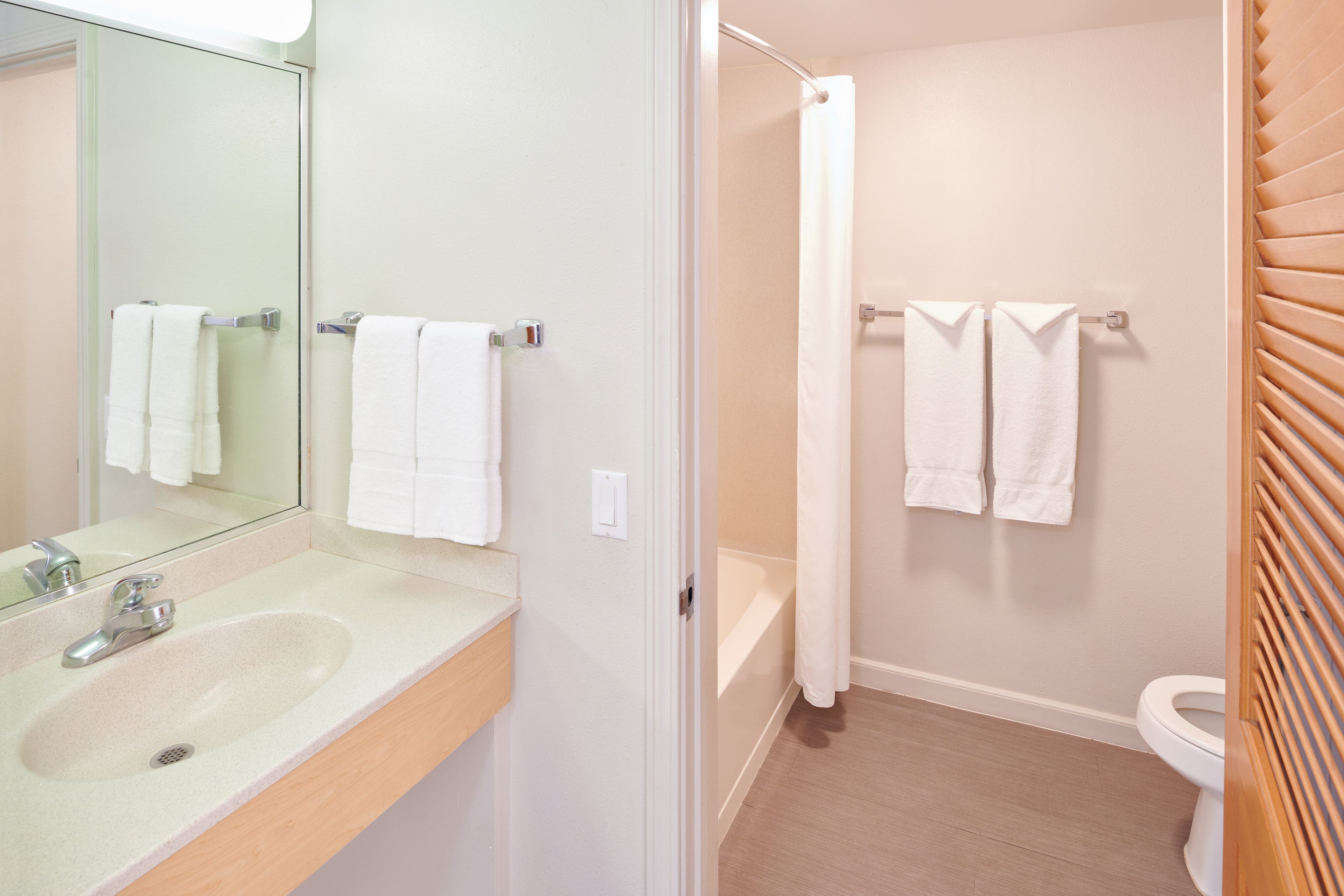 A bathroom with a sink, mirror, towel rack, shower curtain, and toilet.
