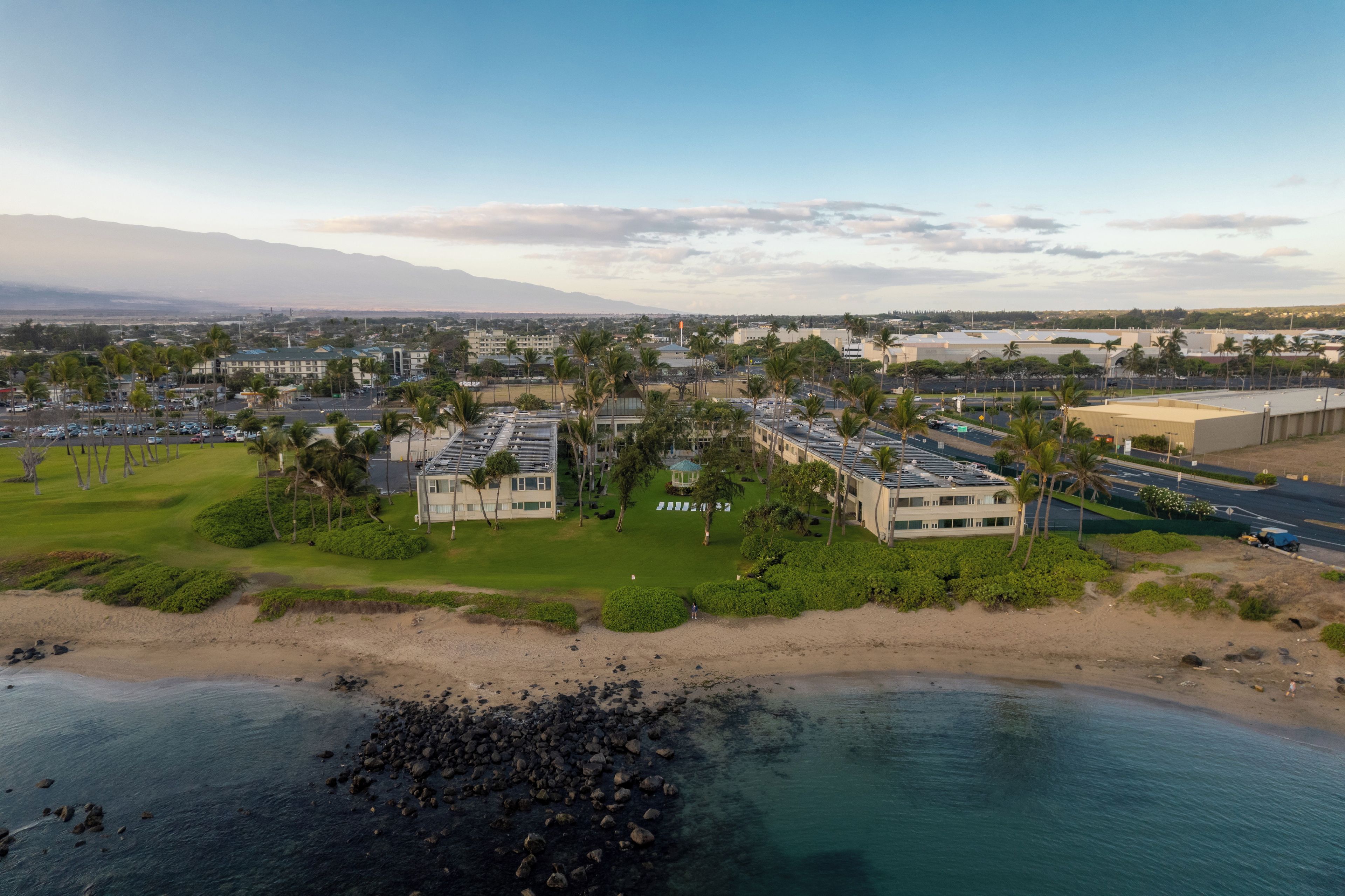 Un resort costero con varias edificaciones, una playa y vista al océano.