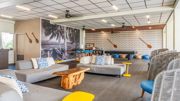 A modern lounge area with sofas, a wooden coffee table, and a pool table. - Maui Beach Hotel (Kahului)