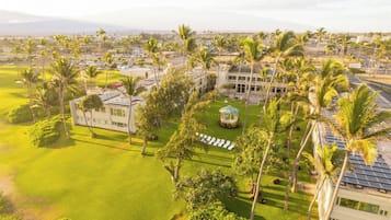 An aerial view of a resort with multiple buildings, palm trees, and a well-maintained lawn.
