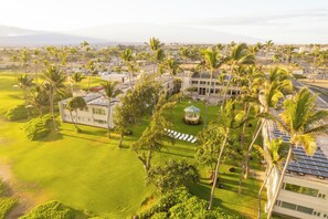 An aerial view of a resort with multiple buildings, palm trees, and a well-maintained lawn. - Maui Beach Hotel (Kahului)
