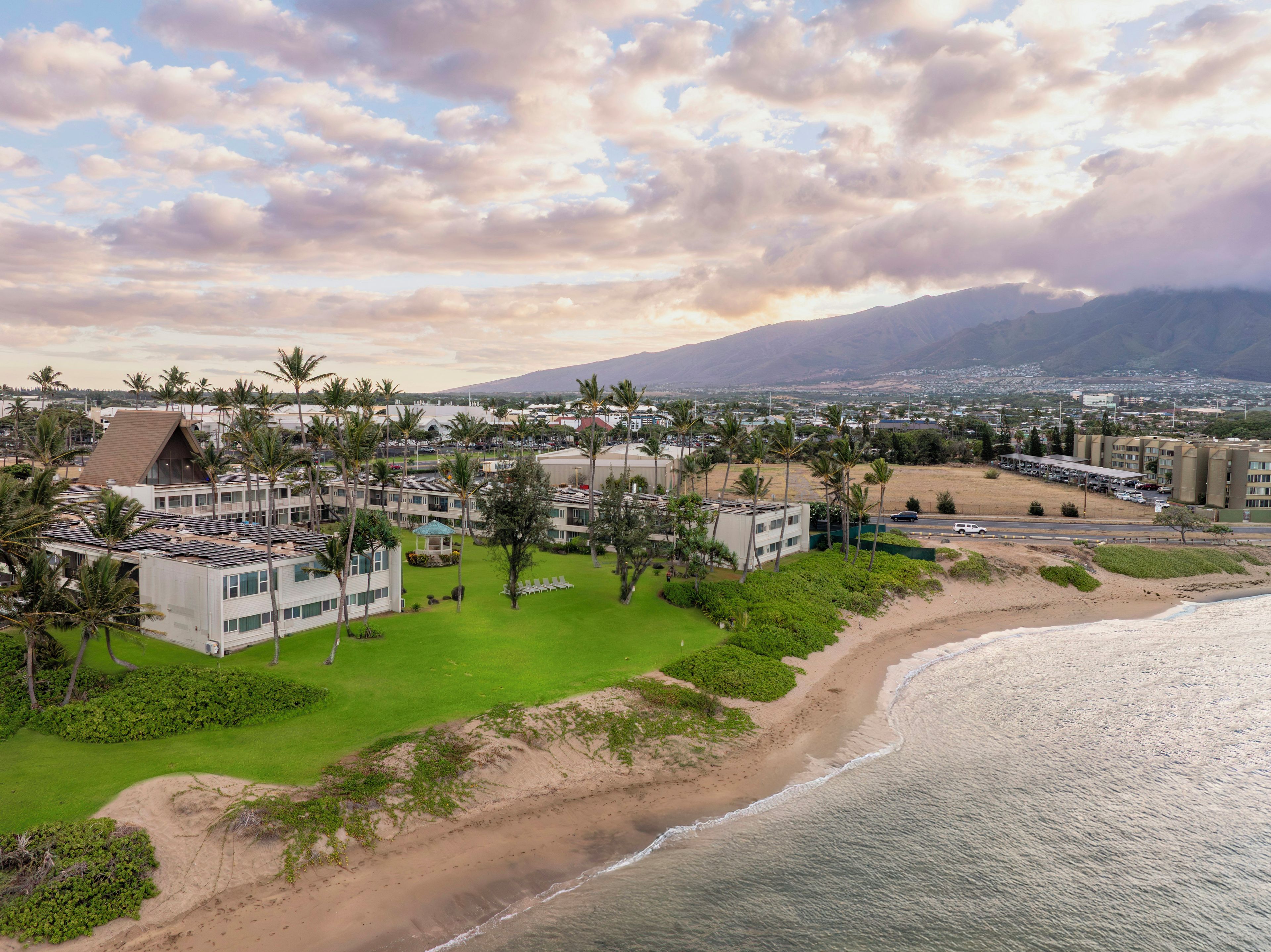 A coastal resort with multiple buildings, a beach, and a mountain in the background.